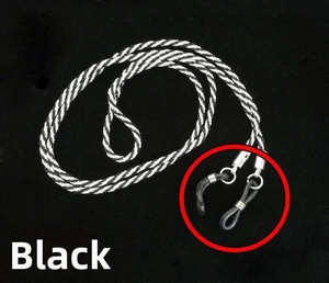 Detail of black and white woven eyewear strap with metal ends and rubber loops