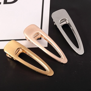 Macro detail of three metallic hair clips in gold, rose gold and silver with brushed texture