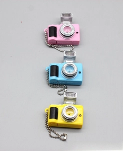 Detailed view of mini toy camera keychains in pink, blue, and yellow with metal chains
