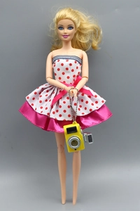Detail of doll camera accessory and polka dot dress on a blonde doll toy