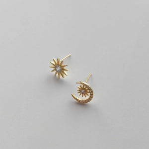 Detail of asymmetric 925 sterling silver star and moon stud earrings in gold with zircon