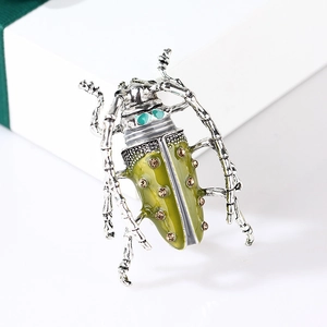 Detailed close-up of a vintage beetle brooch with green enamel and amber rhinestones