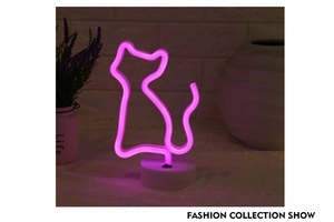 Pink cat-shaped LED neon desk lamp with white base shown against a white brick wall background
