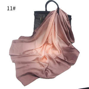 Detail of pink gradient silk scarf draped over a classic black leather tote handbag