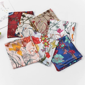 Detail view of stacked floral silk scarves with various elegant butterfly patterns