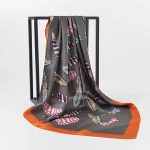 Detailed texture of silk square scarf featuring colorful feather prints and orange borders