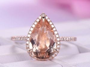 Detailed close-up of a pear-cut pink gemstone ring in rose gold with pavé diamonds