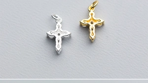 Close-up of polished silver and gold cross pendants with sparkling zircon inlays