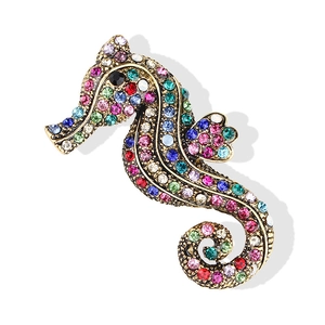 Macro detail of vintage gold seahorse brooch with colorful rhinestones and intricate design