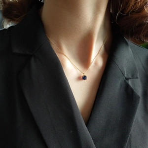 Close-up of a 925 sterling silver gold chain with a deep blue round gemstone pendant