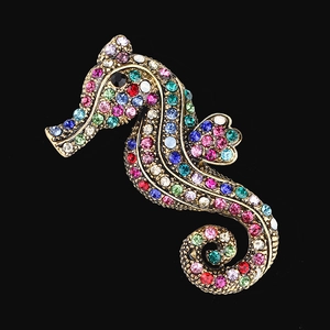 Vintage gold seahorse brooch with vibrant multi-colored rhinestones on black background