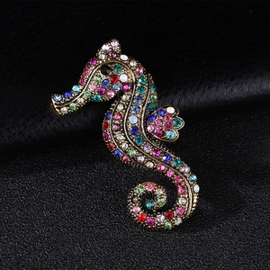 Close-up of vintage seahorse brooch with colorful rhinestones on black leather background