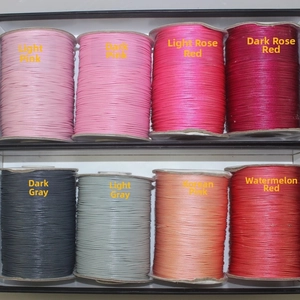 Multiple colors of woven wax cords showing texture in pink, rose red, and grey tones