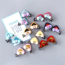 Detail of colorful sequin cat ear hair clips with fuzzy pom-poms and gold stars