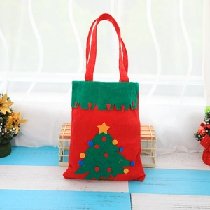 Thick handmade Christmas gift bag with festive felt tree decoration on blue wood floor