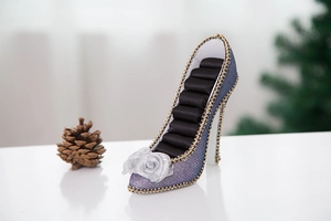 Macro detail of sparkly high heel ring holder with silver flower and velvet slots