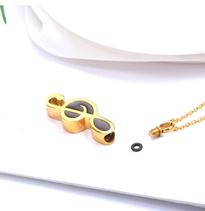 Detail of music note cremation pendant with gold finish and threaded screw opening