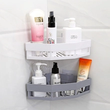 Close-up of white and grey triangular bathroom corner shelves with drainage holes