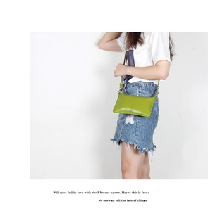 Minimalist green leather envelope crossbody bag shown worn over the shoulder on a model
