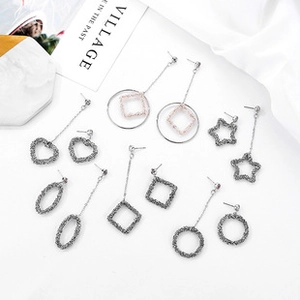 Flat lay of multiple geometric silver earrings set on white fabric with minimalist decor