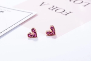 Macro shot of rose gold heart stud earrings with clustered pink purple zirconia stones