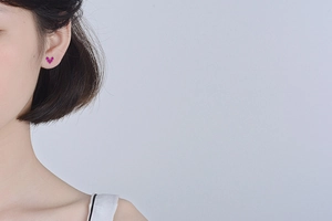 Close-up of elegant rose red heart stud earring worn on model's ear for daily style