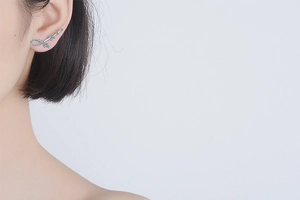 Detailed close-up of silver zircon earrings with infinity and meteor design on model