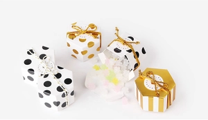 Detalle de mini cajas de regalo hexagonales con patrones dorados y lazos de cinta