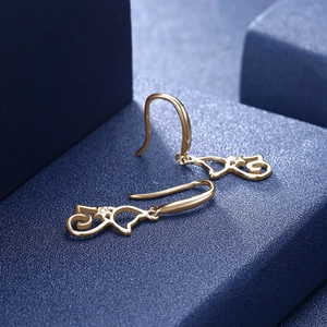 Macro detail of gold cat-shaped earrings with sparkling cubic zirconia on blue stands
