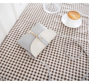 Gray and white PU leather mini handbag with gold hardware on a plaid tablecloth