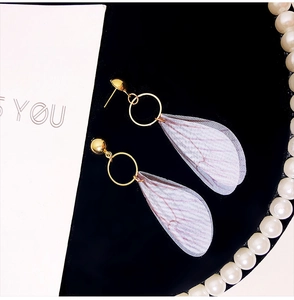 Close-up of handmade gold earrings with translucent purple tulle butterfly wings and pearls