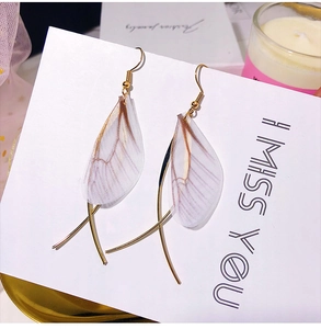 Detailed view of delicate butterfly wing earrings with sheer texture and golden hooks