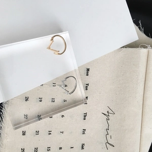 Minimalist V-shaped heartbeat rings in gold and silver finish on acrylic blocks
