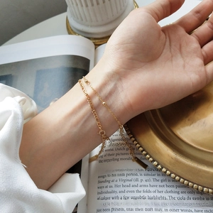 Close-up of double-layer S925 silver beaded bracelet on wrist over a vintage book