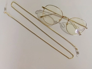 Detail of a golden Venetian chain eyeglass strap with transparent silicone non-slip loops