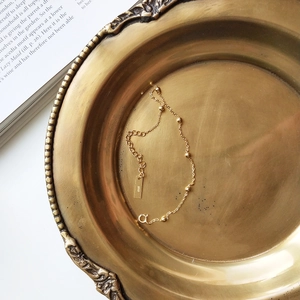 Close-up of S925 sterling silver beaded chain bracelet with adjustable clasp on brass tray