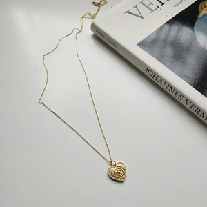 Detail of vintage gold heart pendant with YES MAYBE NO engraving on fine chain