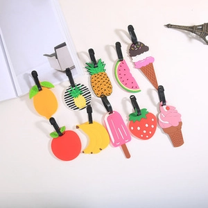 Variety of colorful silicone luggage tags in fruit and ice cream shapes on white surface