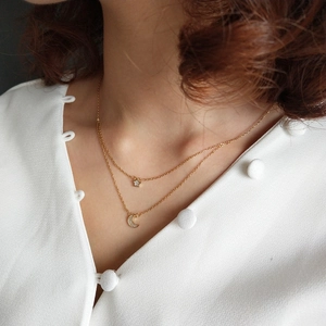 Detail of model wearing a double-layer gold star and crescent moon pendant necklace