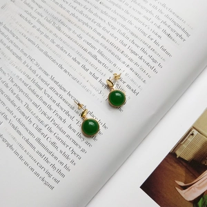 Detailed view of vintage green agate stud earrings with gold finish on a book