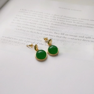 Close-up of gold S925 sterling silver stud earrings with round green agate on book pages