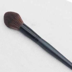 Concave foundation brush with brown gradient bristles and dark handle on white mesh
