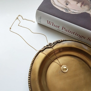 Detail of a vintage-style 925 silver golden necklace with a round embossed pendant on a tray