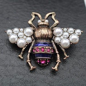 Macro shot of vintage gold bee brooch with pearls, blue enamel and pink rhinestones