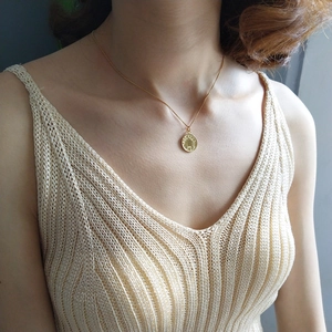 Close-up of a 925 sterling silver gold coin pendant necklace on a female model