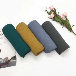Detail view of cotton linen scarves showing vertical wrinkled texture in four muted colors