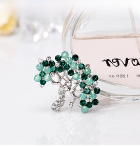 Macro shot of silver alloy tree brooch with sparkling green and clear rhinestones