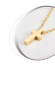 Detailed close-up of a minimalist rose gold cross pendant on a thin link chain