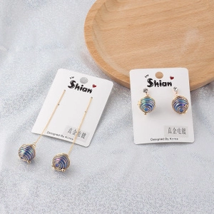 Close-up of gold-plated tassel earrings with purple gradient spiral spheres on a card