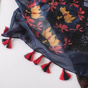 Detail of dark blue floral scarf with red tassels and lightweight cotton linen texture
